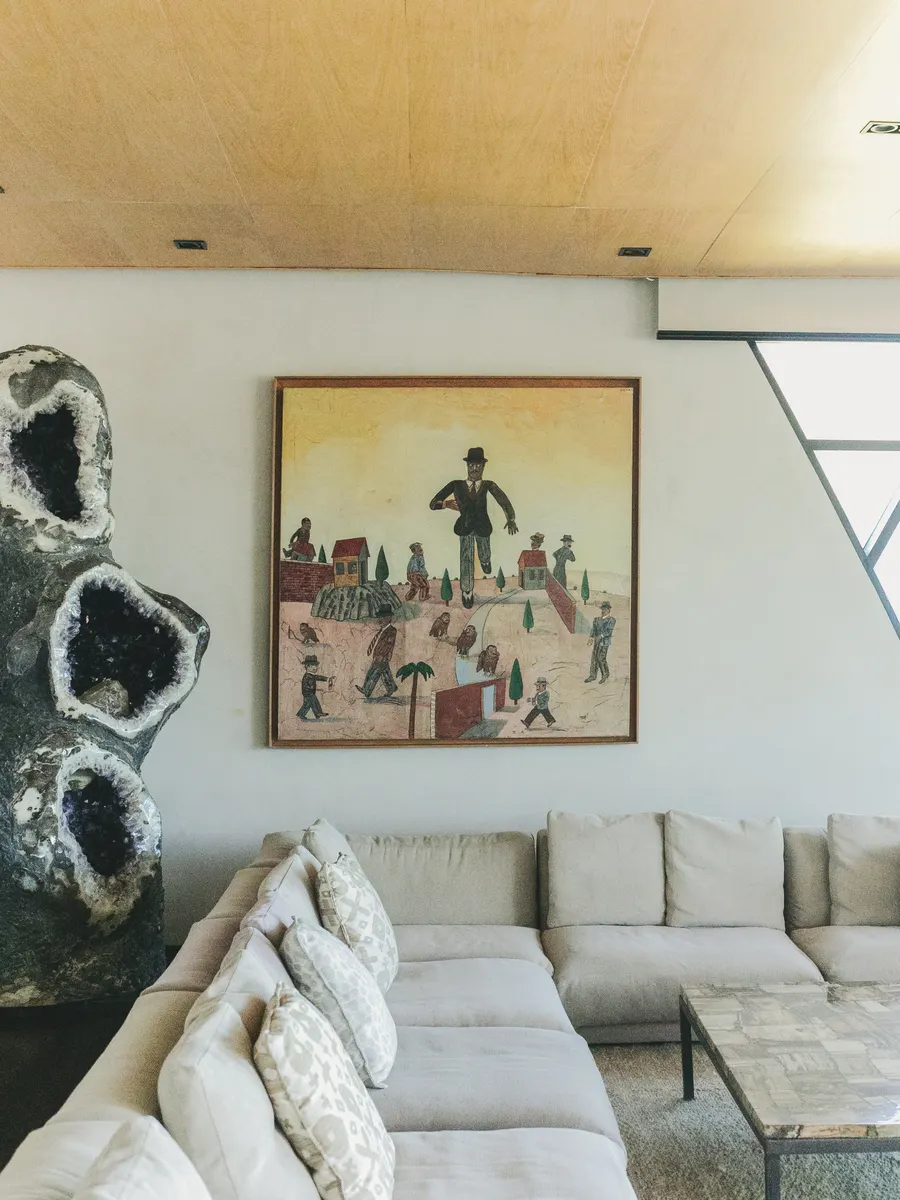 A painting above a sofa, beside a sculpture, in one of the houses