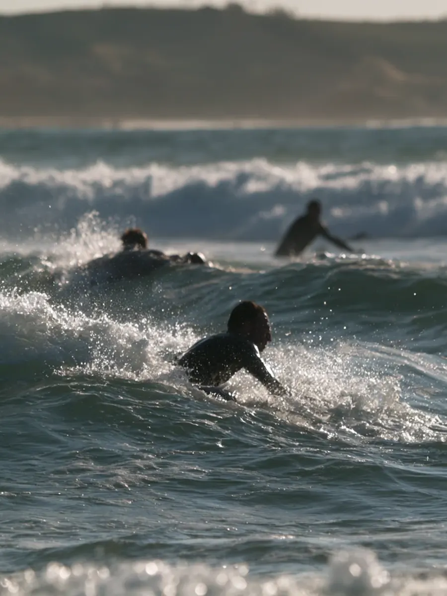Surfers paddling out through the waves