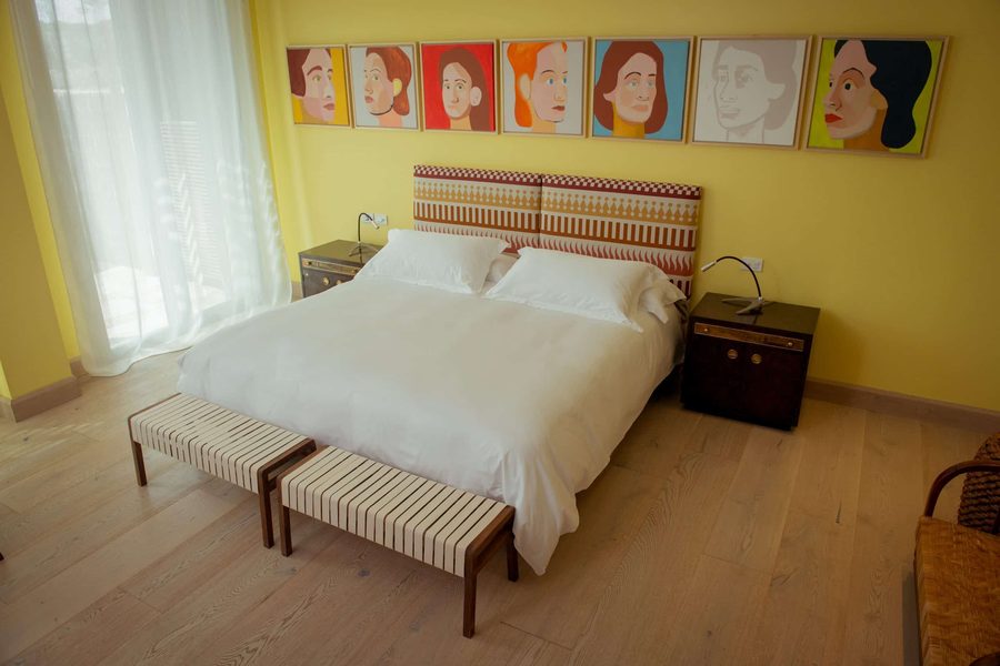 Paulos Suite at Bahía Vik, a yellow room with portraits above the bed
